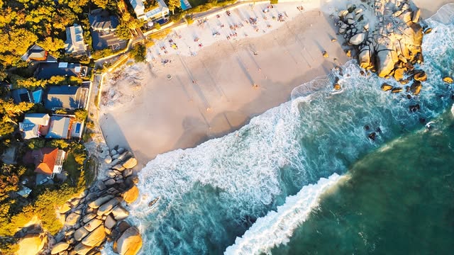 Aerial drone shot of a Cape Town beach with umbrellas and surf